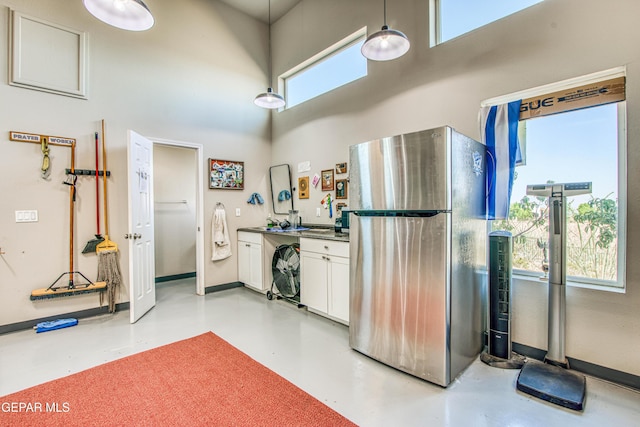 1348 Franklin Wind Place, El Paso, TX 79912 - kitchen with freestanding refrigerator, white cabinetry, a high ceiling, concrete flooring, and dark countertops