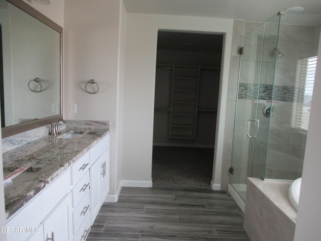 205 Staffs Way, El Paso, TX 79928 - bathroom with a stall shower, double vanity, a walk in closet, a tub, and wood finished floors