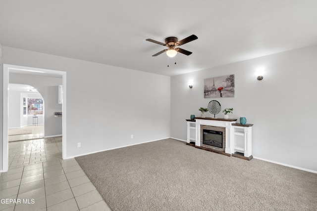 8936 Mount Rushmore Ln, El Paso, TX 79904 - unfurnished living room with ceiling fan, light tile patterned flooring, arched walkways, and a fireplace with raised hearth
