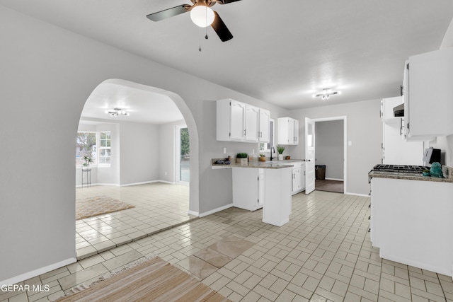 8936 Mount Rushmore Ln, El Paso, TX 79904 - kitchen with arched walkways, ceiling fan, open floor plan, white cabinets, and a peninsula
