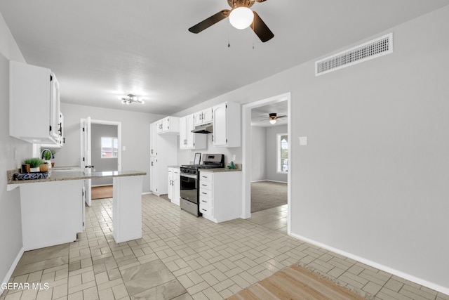 8936 Mount Rushmore Ln, El Paso, TX 79904 - kitchen with stainless steel gas range oven, ceiling fan, under cabinet range hood, white cabinetry, and light countertops