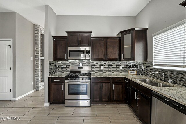 13675 Everingham St, El Paso, TX 79928 - kitchen featuring stainless steel appliances, backsplash, light stone counters, dark brown cabinetry, and glass insert cabinets
