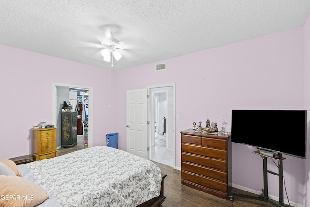 658 Sara Lynn Ct, El Paso, TX 79932 - bedroom featuring dark wood-style flooring, a textured ceiling, a walk in closet, a closet, and ceiling fan
