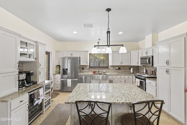 658 Sara Lynn Ct, El Paso, TX 79932 - kitchen featuring stainless steel appliances, a kitchen bar, beverage cooler, backsplash, and white cabinetry