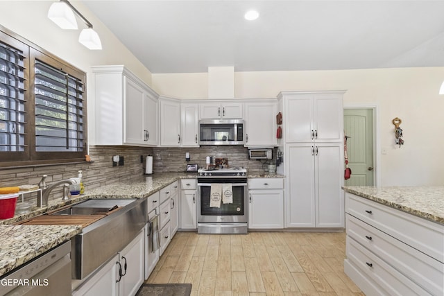 658 Sara Lynn Ct, El Paso, TX 79932 - kitchen with stainless steel appliances, tasteful backsplash, light wood-style floors, and white cabinetry