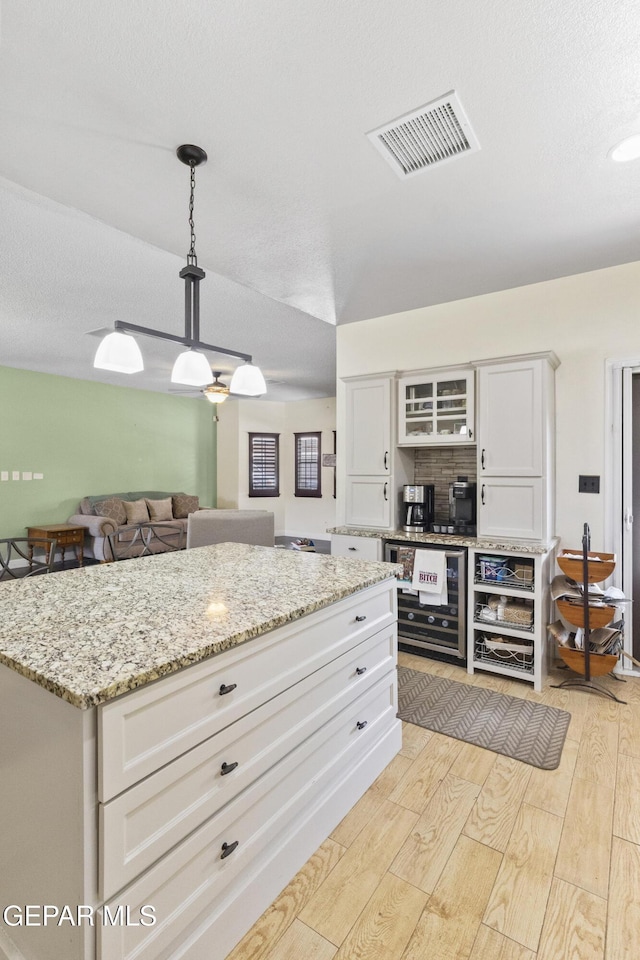 658 Sara Lynn Ct, El Paso, TX 79932 - kitchen featuring light wood-style flooring, white cabinetry, decorative light fixtures, light stone countertops, and glass insert cabinets