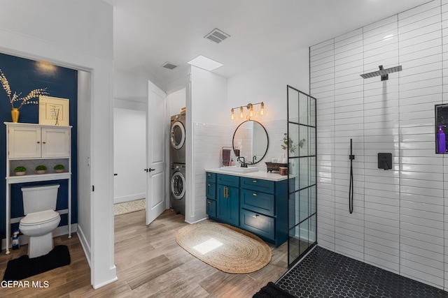 1386 Loma Verde Dr, El Paso, TX 79936 - bathroom featuring stacked washing machine and dryer, tiled shower, vanity, and wood finished floors