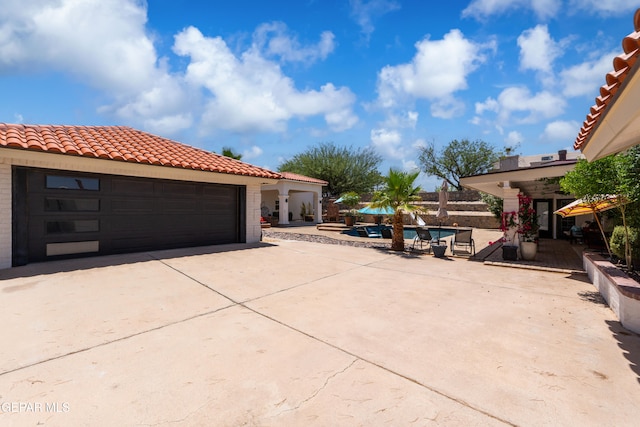 1386 Loma Verde Dr, El Paso, TX 79936 - view of side of property featuring a tile roof, concrete driveway, a garage, and a pool
