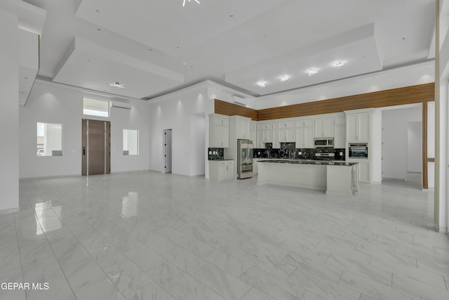 11345 Patricia Ave, El Paso, TX 79936 - kitchen with open floor plan, appliances with stainless steel finishes, dark countertops, white cabinetry, and a kitchen island
