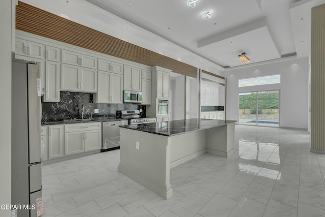 11345 Patricia Ave, El Paso, TX 79936 - kitchen with appliances with stainless steel finishes, a raised ceiling, light marble finish floors, a center island, and tasteful backsplash