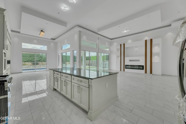 11345 Patricia Ave, El Paso, TX 79936 - kitchen featuring a tray ceiling, light marble finish floors, open floor plan, and a kitchen island