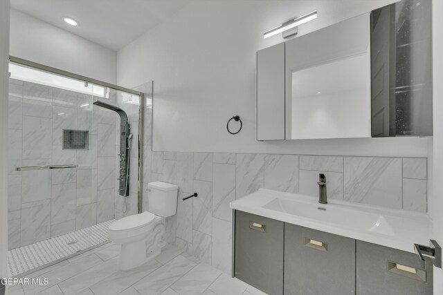 11345 Patricia Ave, El Paso, TX 79936 - full bathroom with vanity, a shower stall, tile walls, a wainscoted wall, and marble look tile flooring