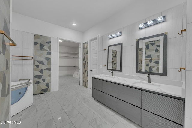 11345 Patricia Ave, El Paso, TX 79936 - full bathroom with double vanity, a walk in closet, tile walls, a tub, and marble look tile flooring