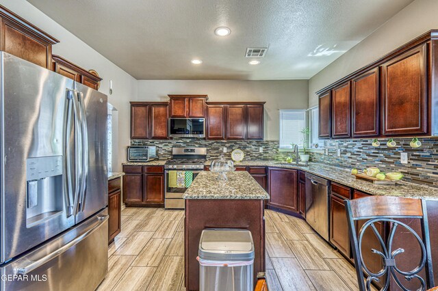 12616 Blazing Star Dr, El Paso, TX 79928 - kitchen featuring stainless steel appliances, wood finish floors, decorative backsplash, light stone counters, and recessed lighting