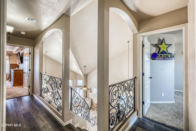 12616 Blazing Star Dr, El Paso, TX 79928 - hallway with arched walkways, dark wood-type flooring, a textured wall, an upstairs landing, and vaulted ceiling