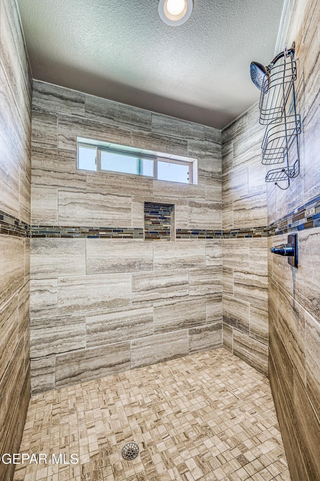 12616 Blazing Star Dr, El Paso, TX 79928 - bathroom featuring a tile shower, healthy amount of natural light, and a textured ceiling