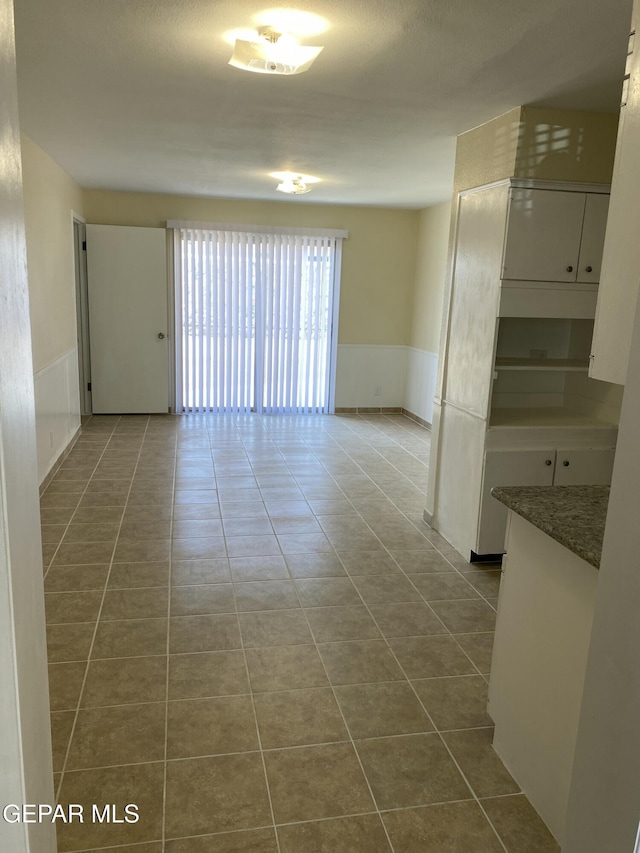 5109 Yvette Ave, El Paso, TX 79924 - spare room featuring dark tile patterned floors and a wainscoted wall