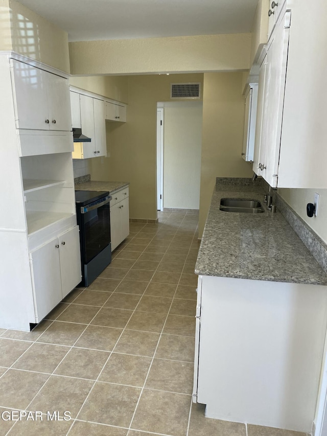 5109 Yvette Ave, El Paso, TX 79924 - kitchen with stainless steel electric range oven, under cabinet range hood, light tile patterned flooring, white cabinetry, and stone countertops
