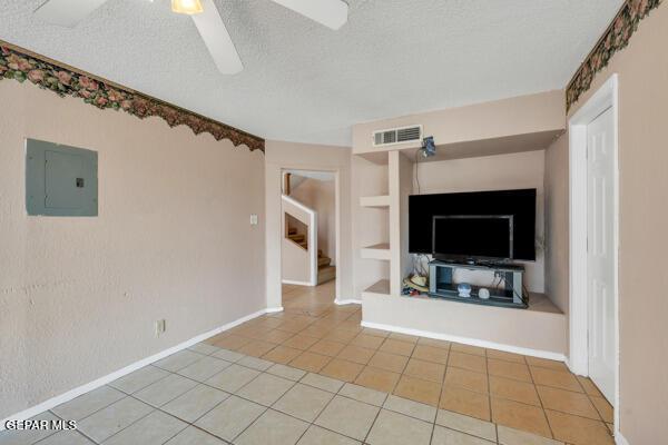 9813 La Morenita Cir, El Paso, TX 79927 - unfurnished living room with electric panel, tile patterned flooring, stairway, ceiling fan, and a textured ceiling