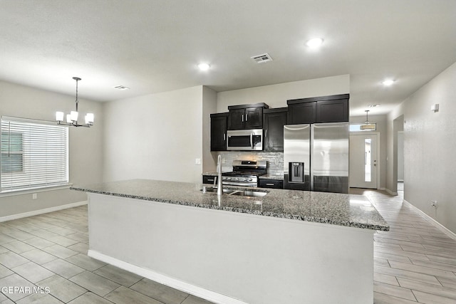 625 Paseo Dulce Ave, El Paso, TX 79928 - kitchen with stainless steel appliances, a chandelier, dark cabinetry, backsplash, and dark stone countertops