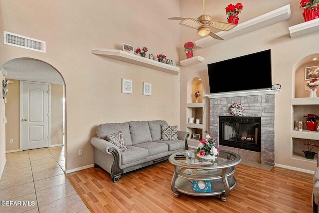 12232 Tierra Rosa Way, El Paso, TX 79938 - living area with built in shelves, a ceiling fan, arched walkways, a towering ceiling, and a fireplace