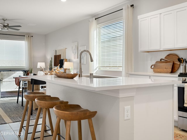13973 Summer Hail Ave, El Paso, TX 79928 - kitchen with a breakfast bar, light countertops, white cabinetry, a ceiling fan, and gas stove