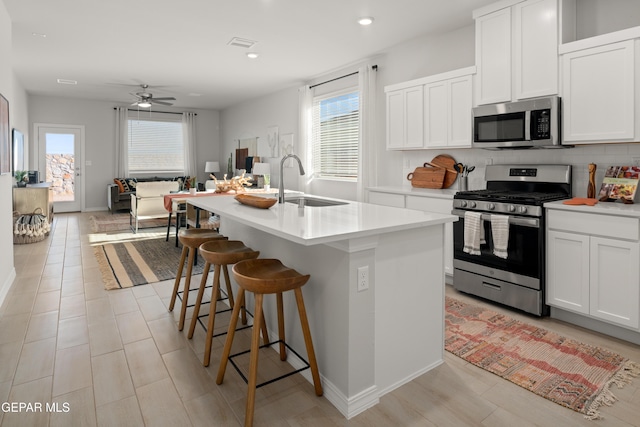13973 Summer Hail Ave, El Paso, TX 79928 - kitchen featuring stainless steel appliances, a ceiling fan, light countertops, an island with sink, and white cabinetry