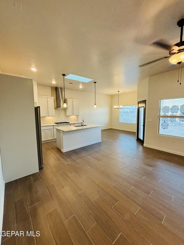 812 Acton St, El Paso, TX 79928 - kitchen featuring wall chimney range hood, ceiling fan, dark wood finished floors, white cabinetry, and open floor plan