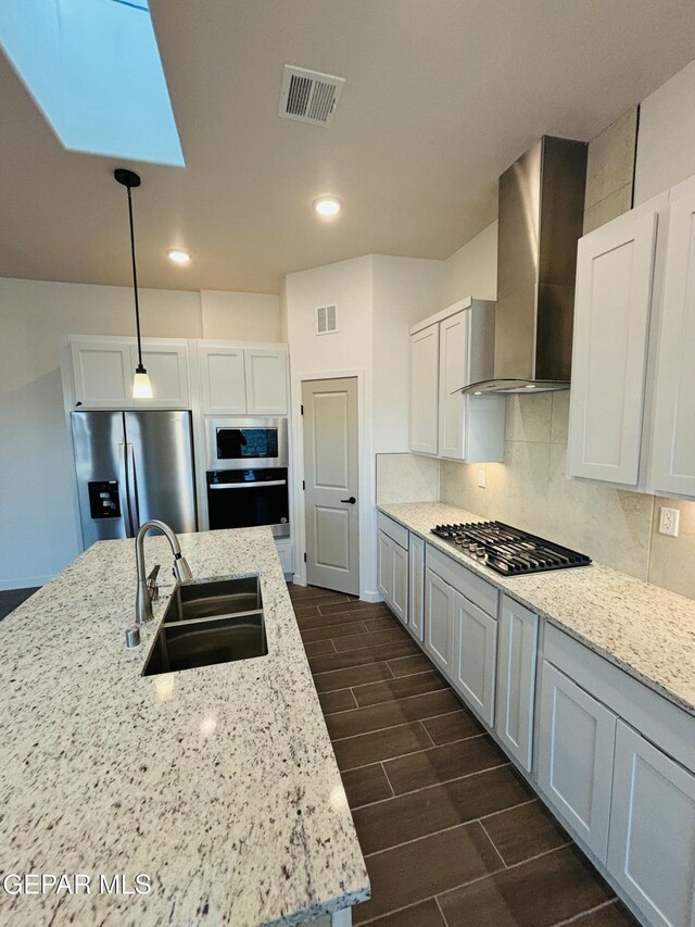 812 Acton St, El Paso, TX 79928 - kitchen with appliances with stainless steel finishes, wall chimney exhaust hood, wood tiled floors, backsplash, and light stone counters