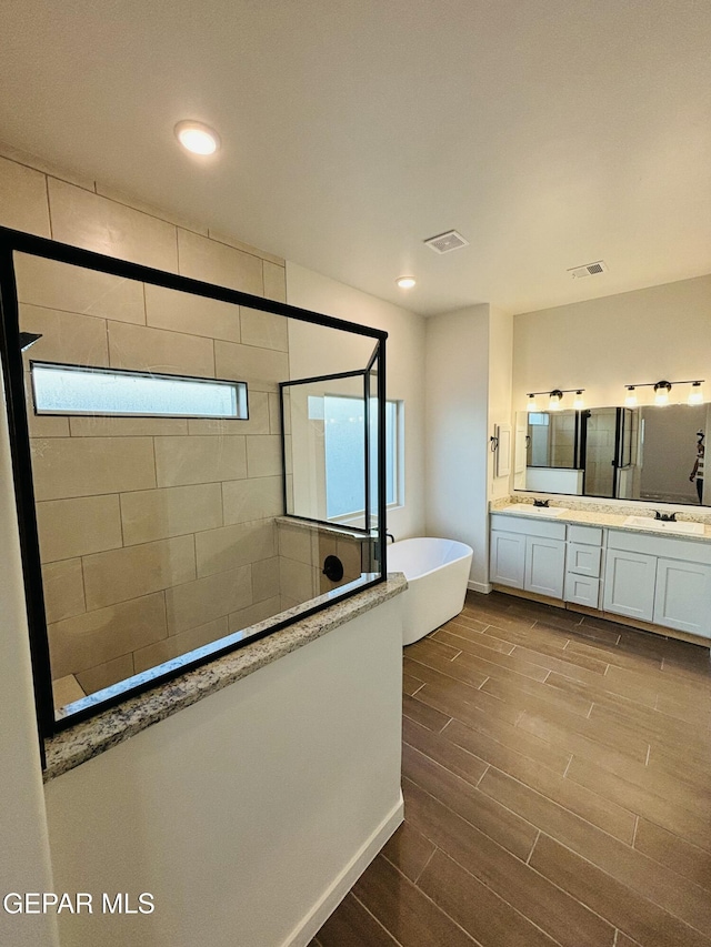 812 Acton St, El Paso, TX 79928 - bathroom with double vanity, walk in shower, a freestanding tub, wood tiled floors, and recessed lighting