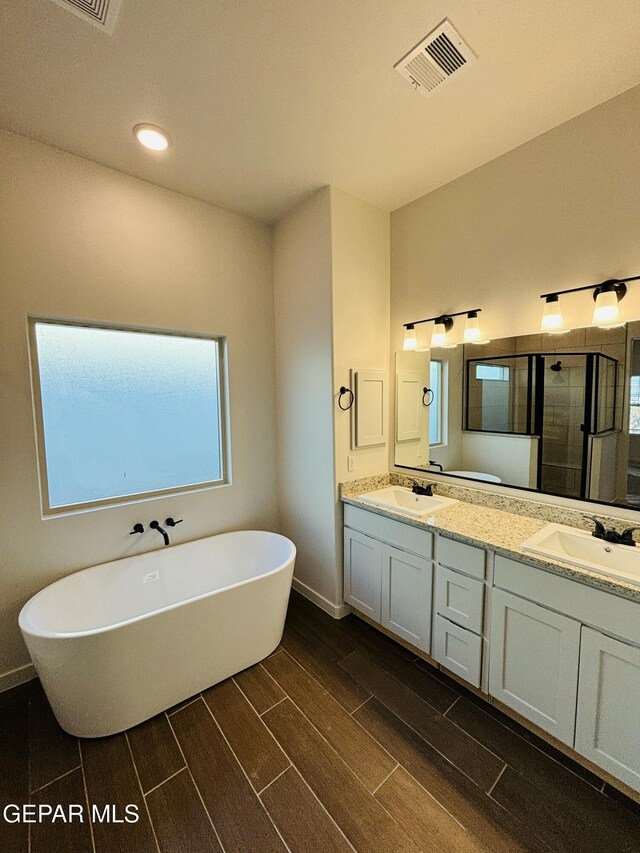 812 Acton St, El Paso, TX 79928 - bathroom featuring double vanity, wood tiled floors, a soaking tub, a stall shower, and recessed lighting