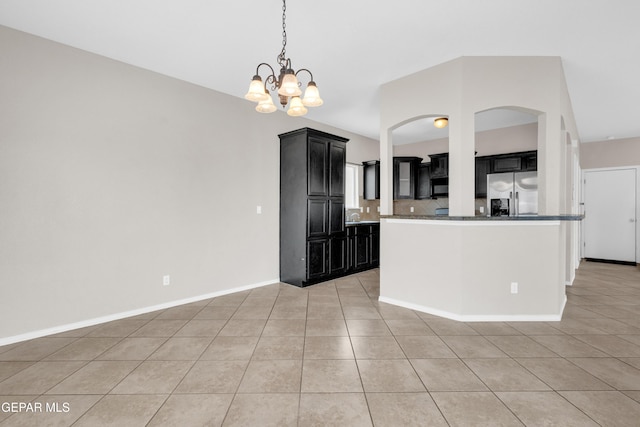 10925 Ray Mena Ln, El Paso, TX 79934 - kitchen with stainless steel fridge, light tile patterned flooring, dark cabinetry, a chandelier, and arched walkways