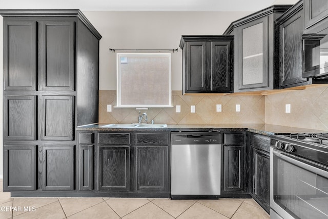 10925 Ray Mena Ln, El Paso, TX 79934 - kitchen featuring appliances with stainless steel finishes, light tile patterned flooring, tasteful backsplash, dark stone counters, and dark cabinetry