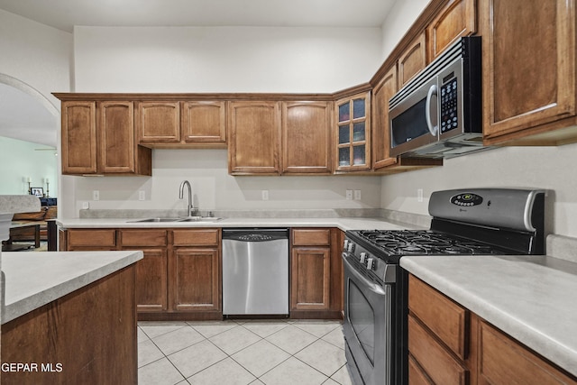 13788 Paseo Verde Dr, El Paso, TX 79928 - kitchen with appliances with stainless steel finishes, light countertops, light tile patterned floors, glass insert cabinets, and arched walkways