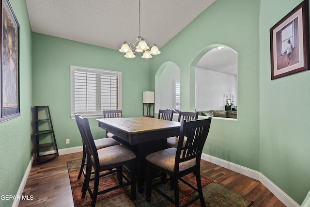 13788 Paseo Verde Dr, El Paso, TX 79928 - dining space featuring dark wood finished floors, a chandelier, arched walkways, a textured ceiling, and vaulted ceiling