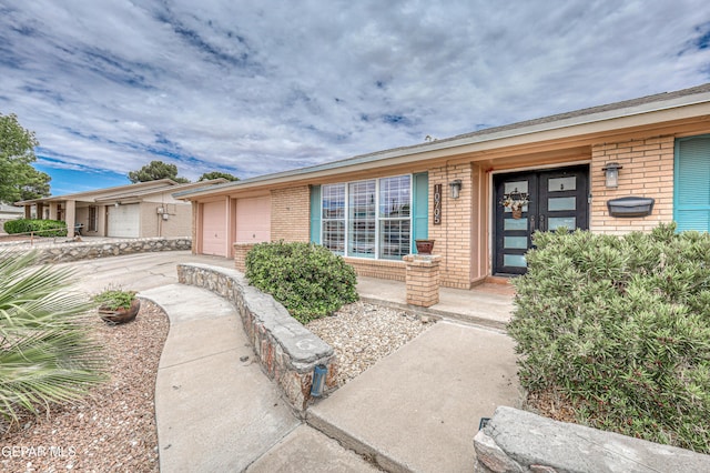 10705 Vista Alegre Dr, El Paso, TX 79935 - view of exterior entry with brick siding, driveway, a garage, and a porch