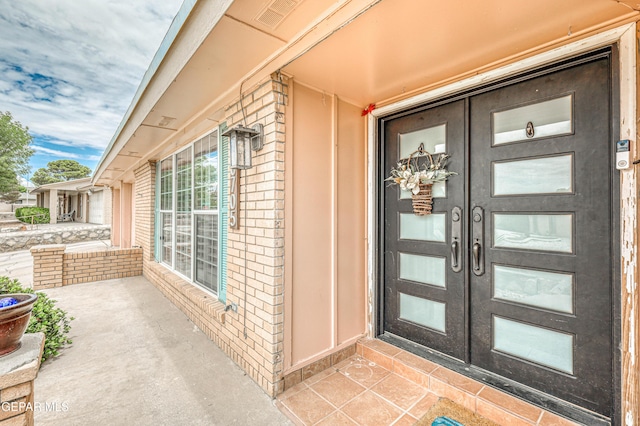 10705 Vista Alegre Dr, El Paso, TX 79935 - doorway to property featuring french doors, brick siding, and a porch