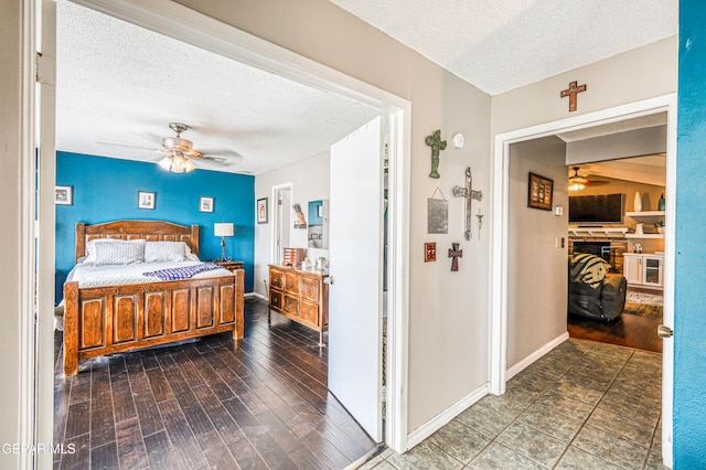 10705 Vista Alegre Dr, El Paso, TX 79935 - bedroom with a textured ceiling, a stone fireplace, wood finished floors, and a ceiling fan