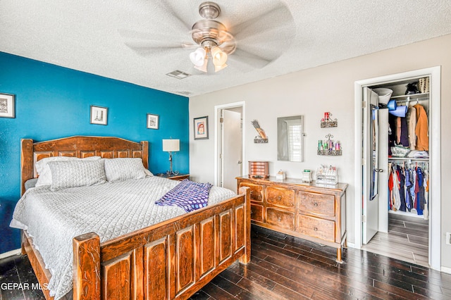 10705 Vista Alegre Dr, El Paso, TX 79935 - bedroom featuring a closet, dark wood-type flooring, a textured ceiling, a ceiling fan, and a walk in closet