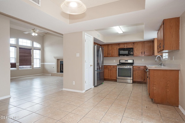 3340 Tierra Yvette Ln, El Paso, TX 79938 - kitchen featuring appliances with stainless steel finishes, a tray ceiling, brown cabinets, open floor plan, and light tile patterned floors