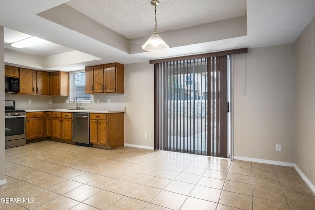 3340 Tierra Yvette Ln, El Paso, TX 79938 - kitchen featuring stainless steel appliances, a tray ceiling, brown cabinets, light countertops, and light tile patterned flooring