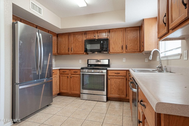 3340 Tierra Yvette Ln, El Paso, TX 79938 - kitchen with stainless steel appliances, brown cabinets, and light tile patterned floors