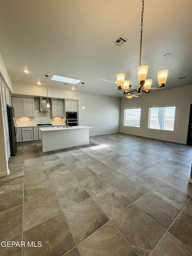 13066 Emerald Isle St, El Paso, TX 79928 - kitchen with freestanding refrigerator, wall chimney exhaust hood, open floor plan, a chandelier, and stainless steel microwave