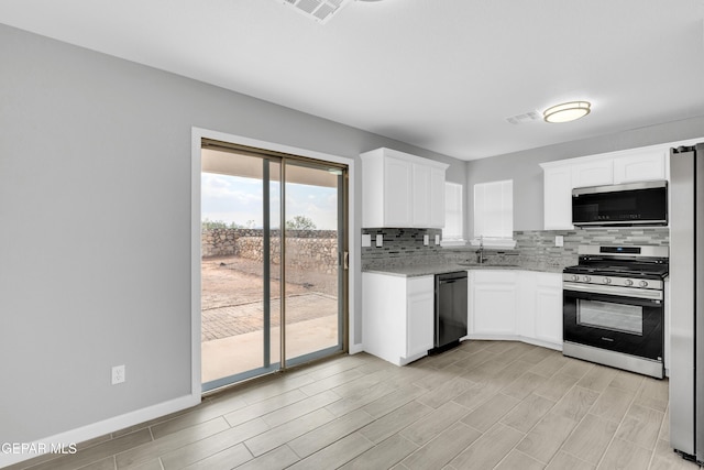 6913 Jericho Tree Dr, El Paso, TX 79934 - kitchen with stainless steel appliances, backsplash, white cabinets, and light wood finished floors