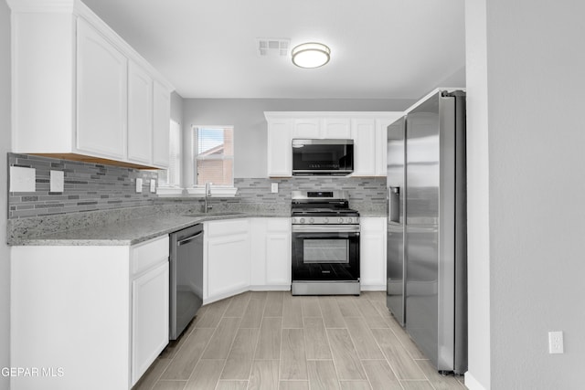6913 Jericho Tree Dr, El Paso, TX 79934 - kitchen featuring appliances with stainless steel finishes, backsplash, white cabinetry, light stone counters, and light wood finished floors