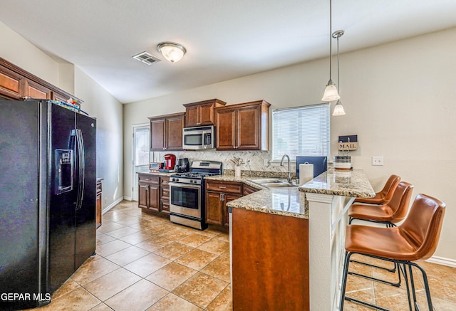 12257 Gaudi Way, El Paso, TX 79938 - kitchen featuring stainless steel appliances, a peninsula, tasteful backsplash, a breakfast bar, and light stone counters
