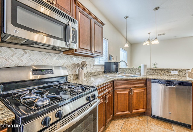 12257 Gaudi Way, El Paso, TX 79938 - kitchen with appliances with stainless steel finishes, a peninsula, pendant lighting, light tile patterned flooring, and light stone counters