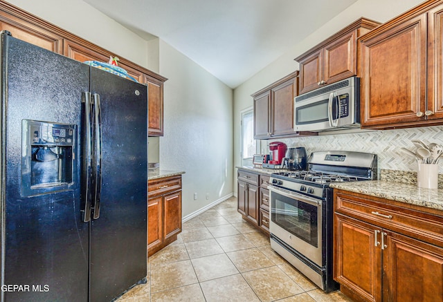 12257 Gaudi Way, El Paso, TX 79938 - kitchen with stainless steel appliances, tasteful backsplash, vaulted ceiling, light stone counters, and light tile patterned floors