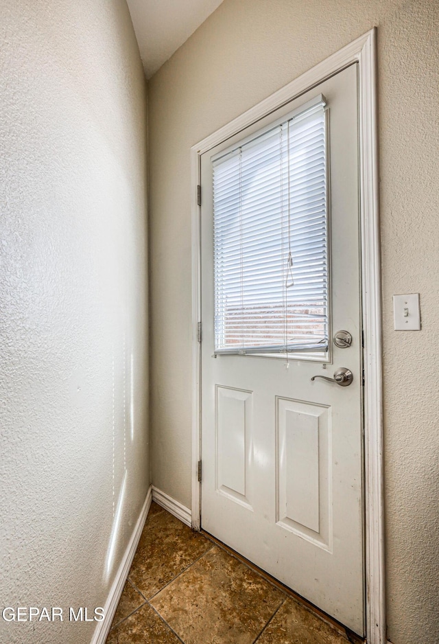 12257 Gaudi Way, El Paso, TX 79938 - doorway to outside with a textured wall and stone finish flooring