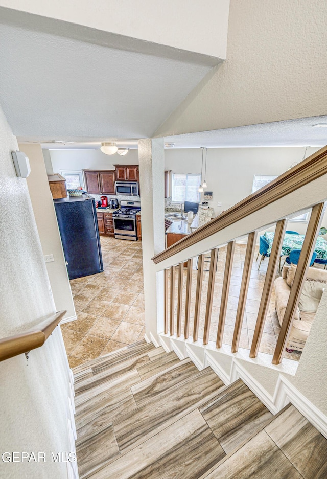 12257 Gaudi Way, El Paso, TX 79938 - stairs with wood finished floors, a textured wall, and vaulted ceiling